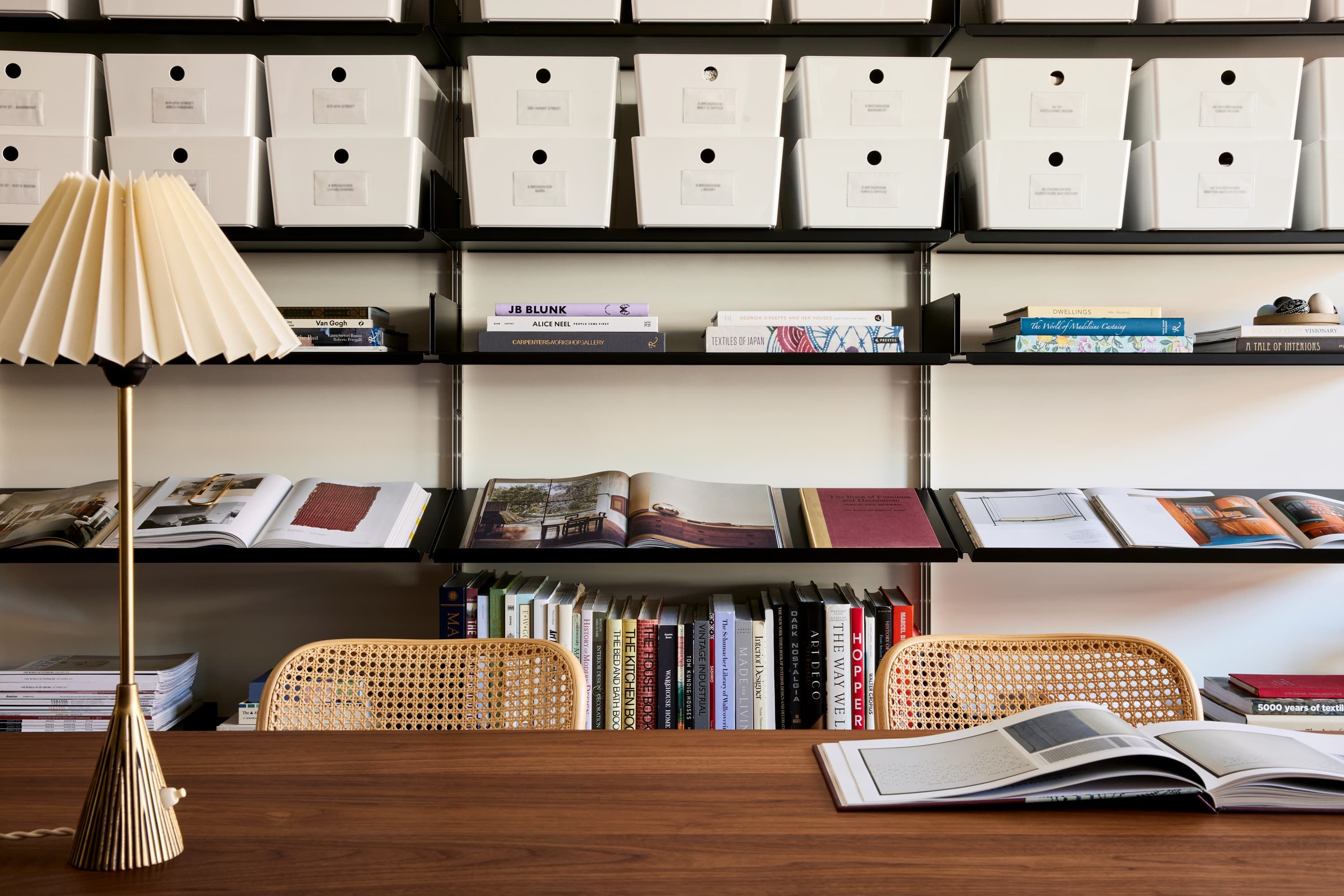 Inside the Jesse Parris-Lamb studio — a walnut worktable with cane chairs against shelves of archive boxes and design books