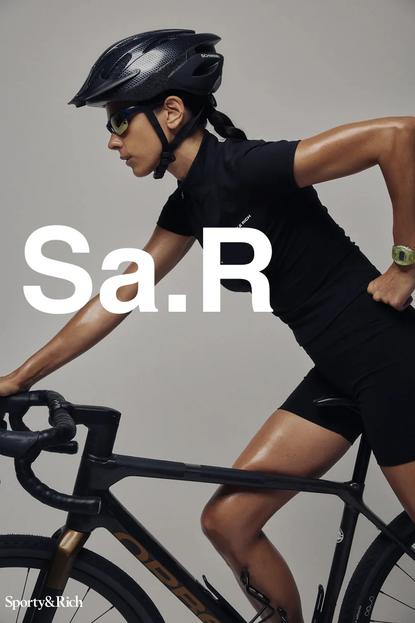 Sporty&Rich — Cyclist leaning over a bicycle with white Sa.R typography